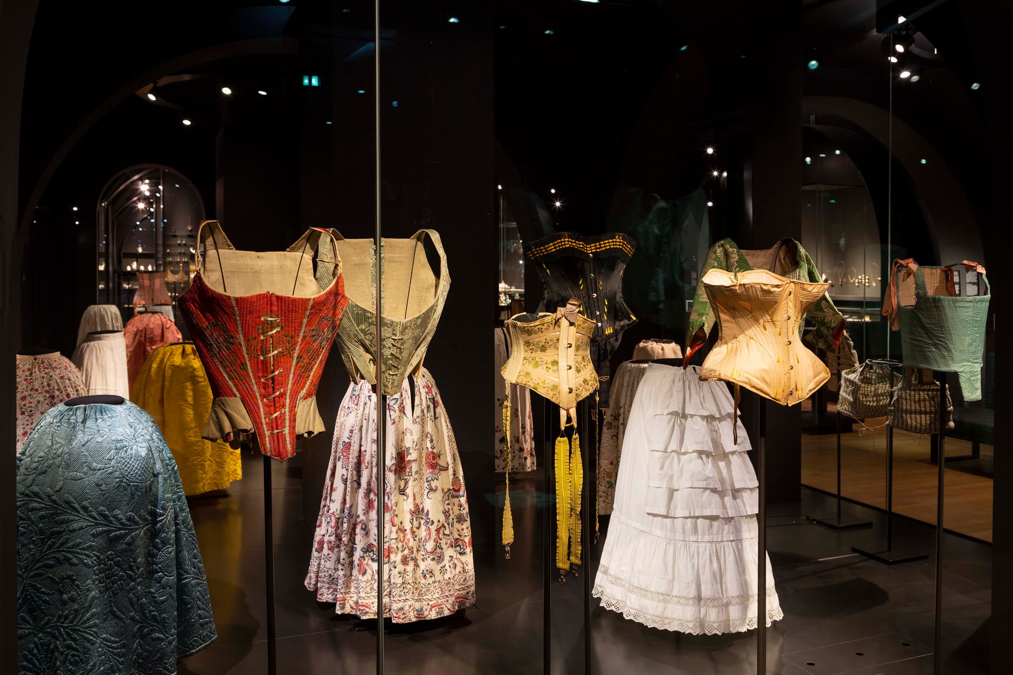 An arrangement of historical textile dresses on display at a museum
